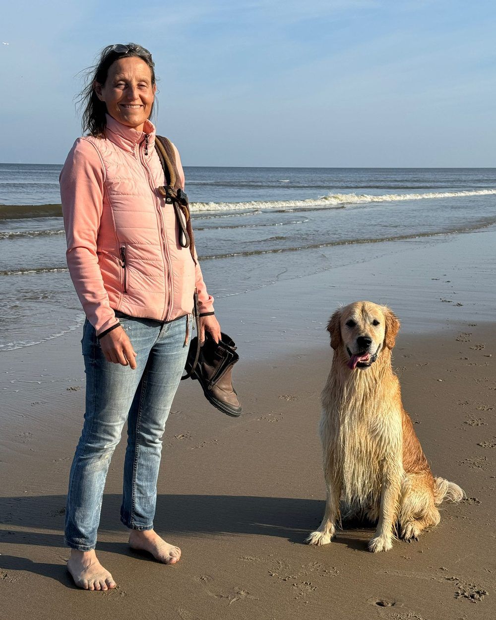 Ellen op blote voeten met haar hond aan het strand